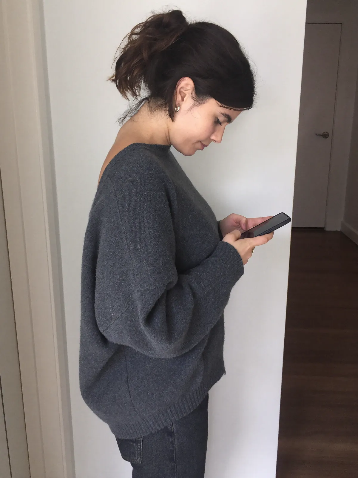 A woman hunched over her phone with a rounded upper back
